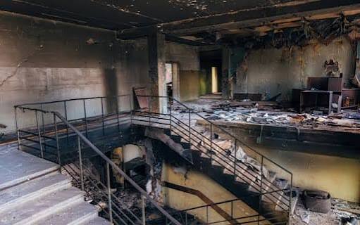 A fire-damaged commercial interior stairwell and office space