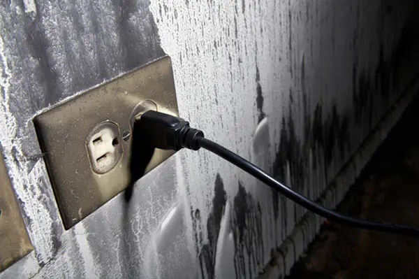 A scorched electrical outlet with soot damage spreading up the wall
