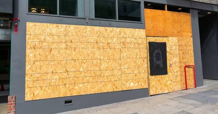 A storefront secured with plywood board-up after fire damage