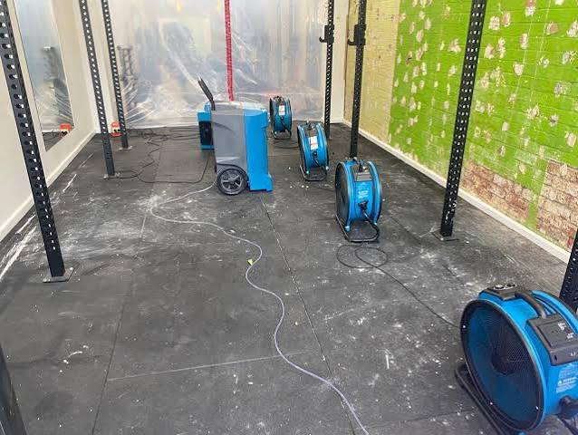 Industrial air movers and a dehumidifier drying out a fire- and water-damaged commercial space