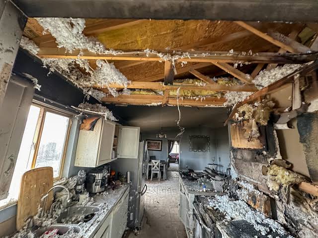 A home kitchen with fire damage exposing the ceiling insulation and burned framing