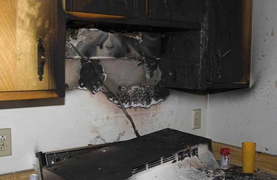 A burned kitchen range hood and cabinet after a stovetop fire
